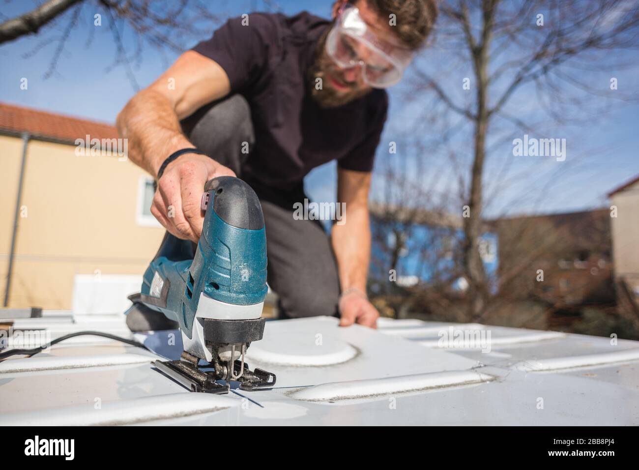 Hombre cortando un agujero en el techo de su caravana Foto de stock