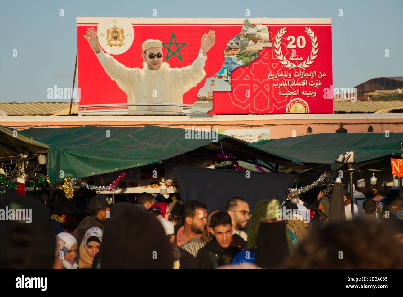 Gente caminando por el famoso mercado Jemaa el-Fna, bajo la mirada de su presidente Mohammed VI Foto de stock