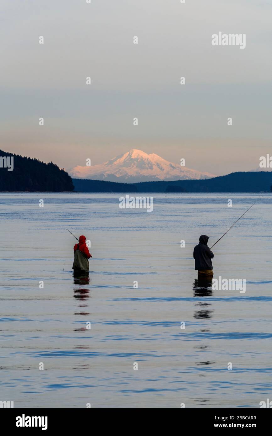 Dos hombres pescando en el océano en Cherry Point Beach cerca de Cowichan Bay, British Columbia. Mt. Baker en el estado de Washington está en el fondo. Foto de stock