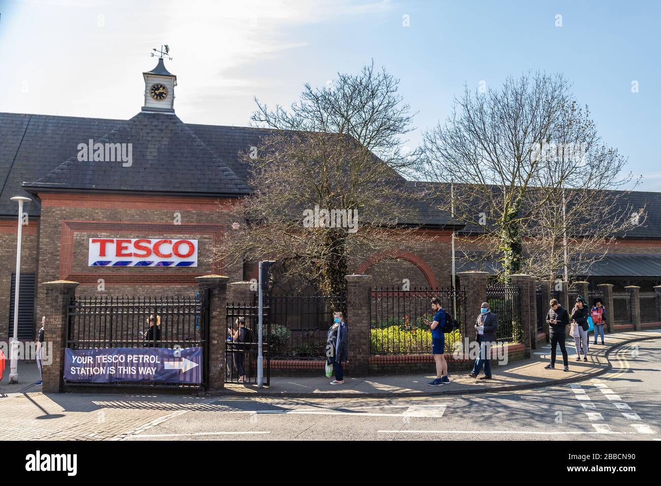 LONDRES, Reino Unido - 26 DE MARZO de 2020: Largas colas fuera de una tienda Tesco causadas por las reglas de distanciamiento social para ayudar a prevenir la propagación del Coronavirus (COVID- Foto de stock