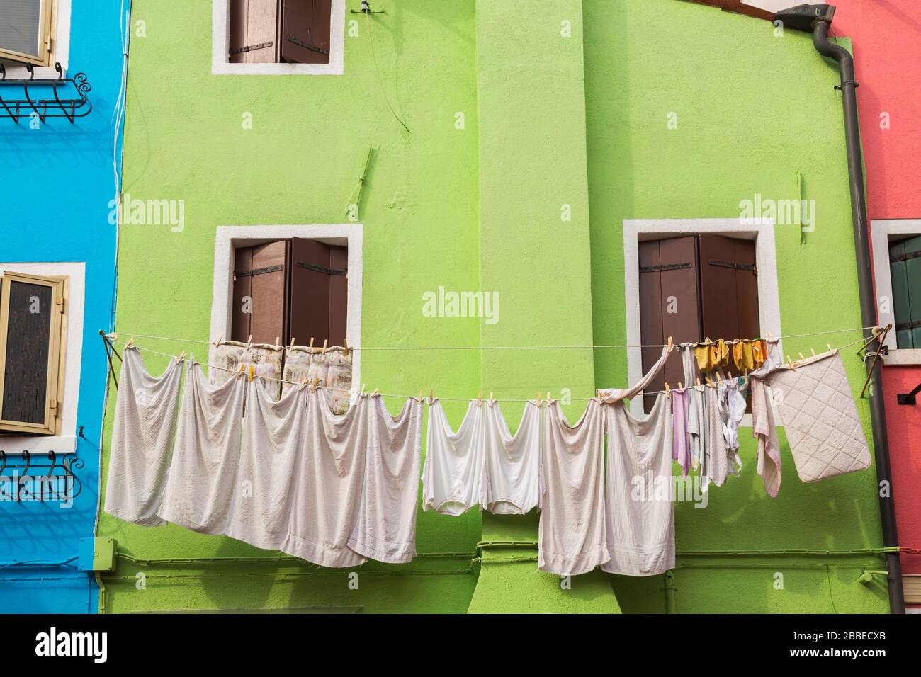 Fachada de la casa de estuco verde decorada con cortina sobre la puerta de entrada y ropa lavada en el tendedero, Isla Burano, Laguna veneciana, Venecia, Véneto, Italia Foto de stock