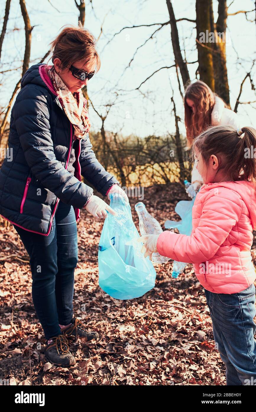 Familia limpiando un bosque. Voluntarios recogiendo residuos plásticos en bolsas. Concepto de contaminación plástica y demasiados residuos plásticos. Cuestión ambiental. E Foto de stock