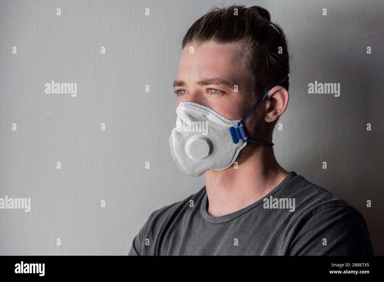 Retrato de un hombre en una máscara médica, durante la cuarentena en el momento de la epidemia de coronavirus, covid-19. Mira y espera que ellos inventen un Foto de stock
