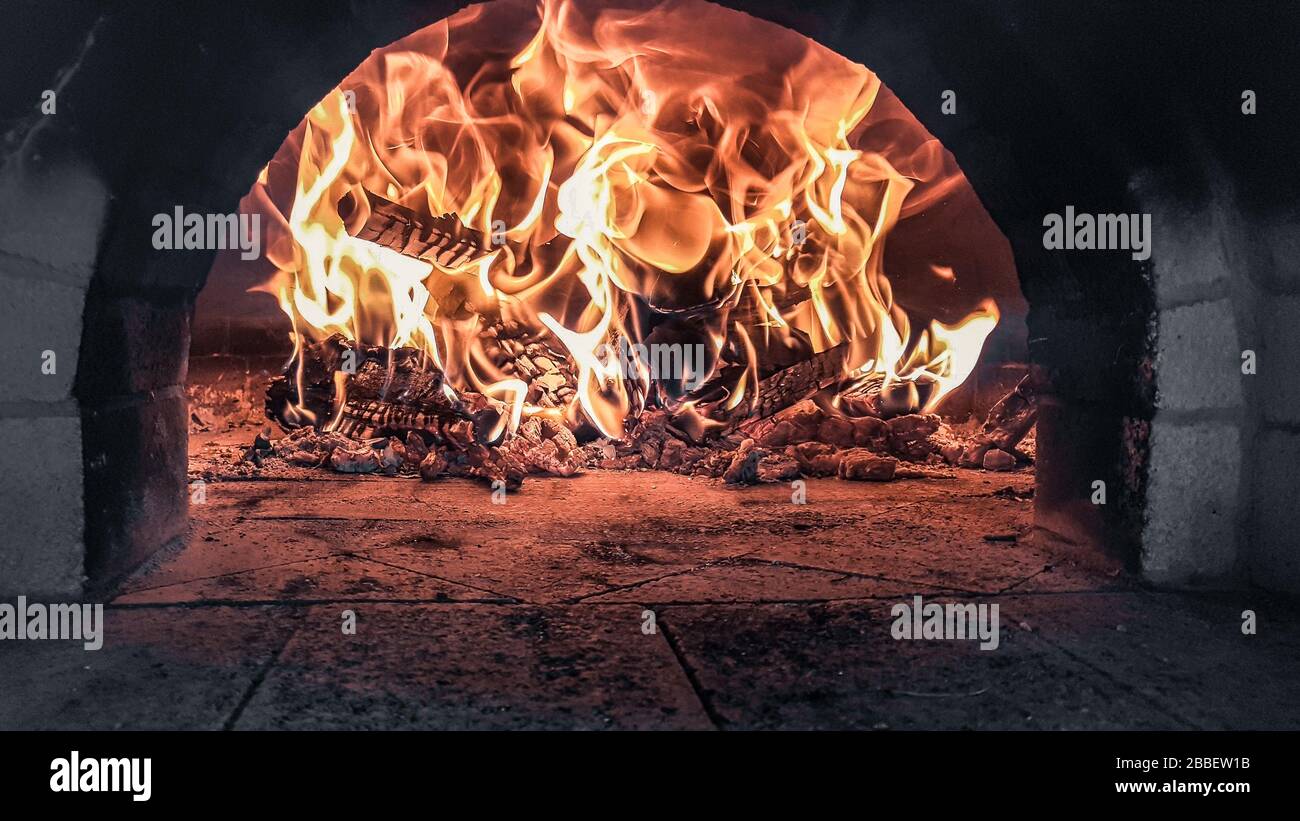 Fuego rojo caliente ardiendo dentro de un horno de leña de pizza con llamas rojas de color naranja Bulgaria Foto de stock