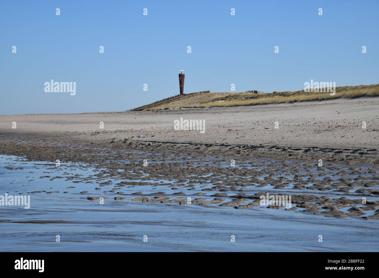 Maasvlakte Beach, Rotterdam, países Bajos-Marzo 2020: Vista de ángulo bajo sobre la playa con charco de marea en un día soleado con la icónica torre de radar de acero i Foto de stock