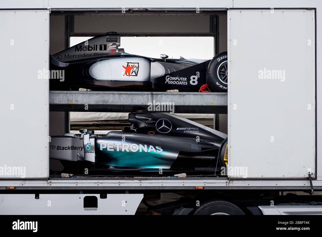 Dos Mercedes-Benz Fórmula 1 coches de carreras de diferentes años están siendo readied para descargar de un transportista de coches en el Festival de velocidad de Goodwood. Foto de stock