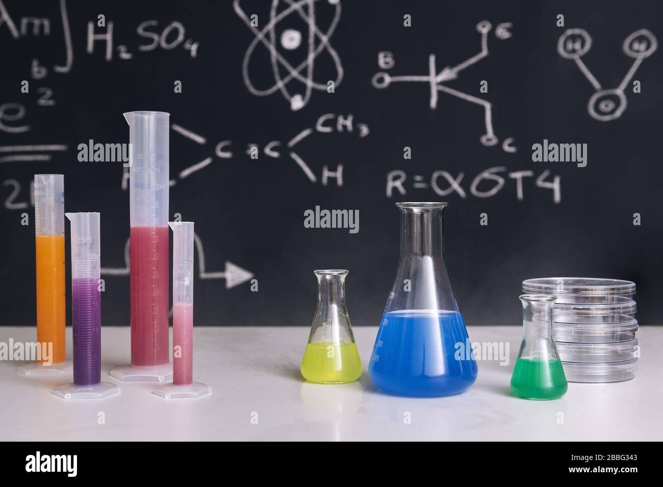 mesa de clase con matraces con productos químicos coloreados, instrumentos  y un pizarrón dibujado con la enseñanza de la ciencia en el fondo, la  educación de las ciencias químicas Fotografía de stock -