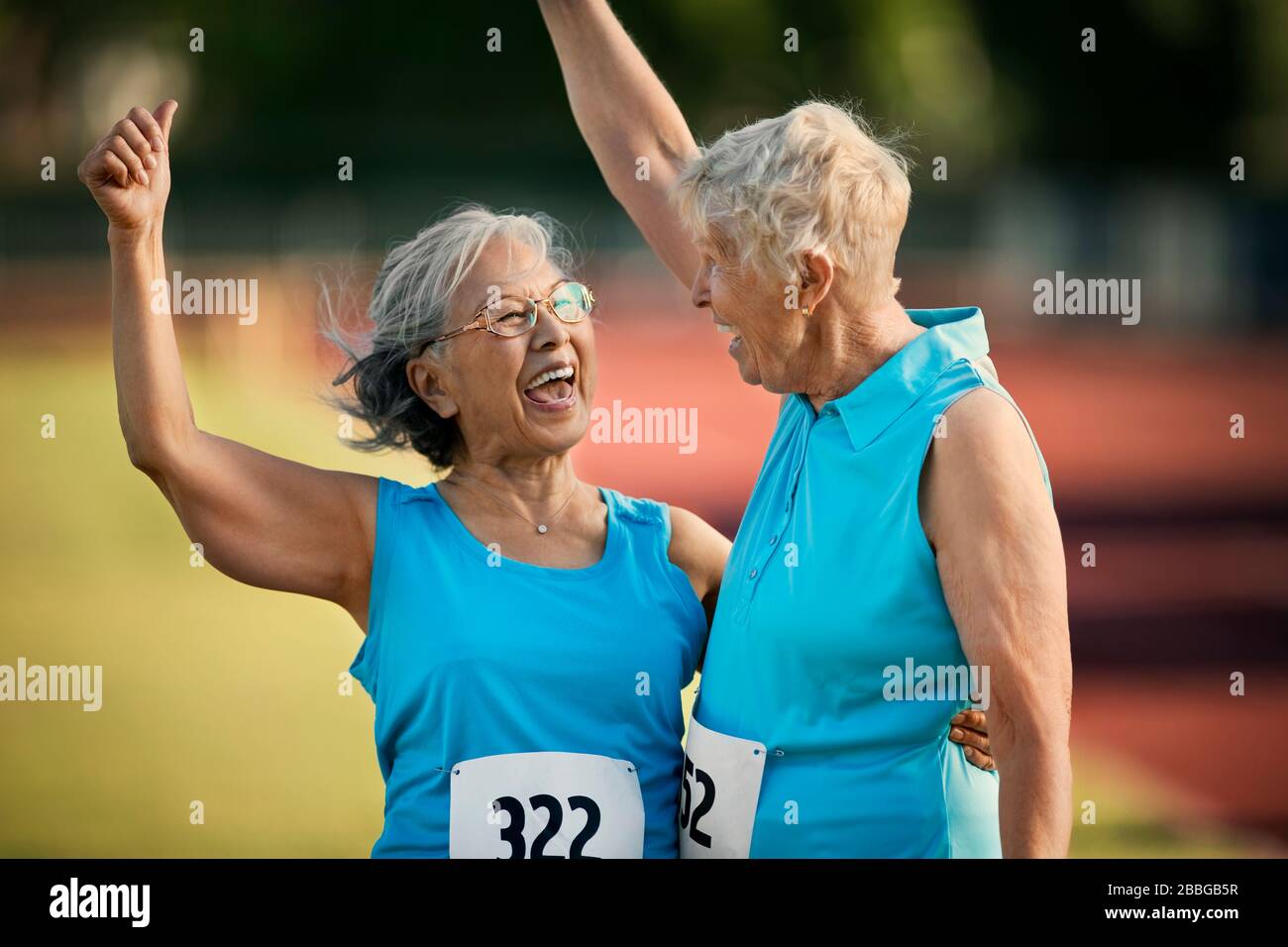Dos mujeres mayores felices riendo después de competir en un evento atlético Foto de stock