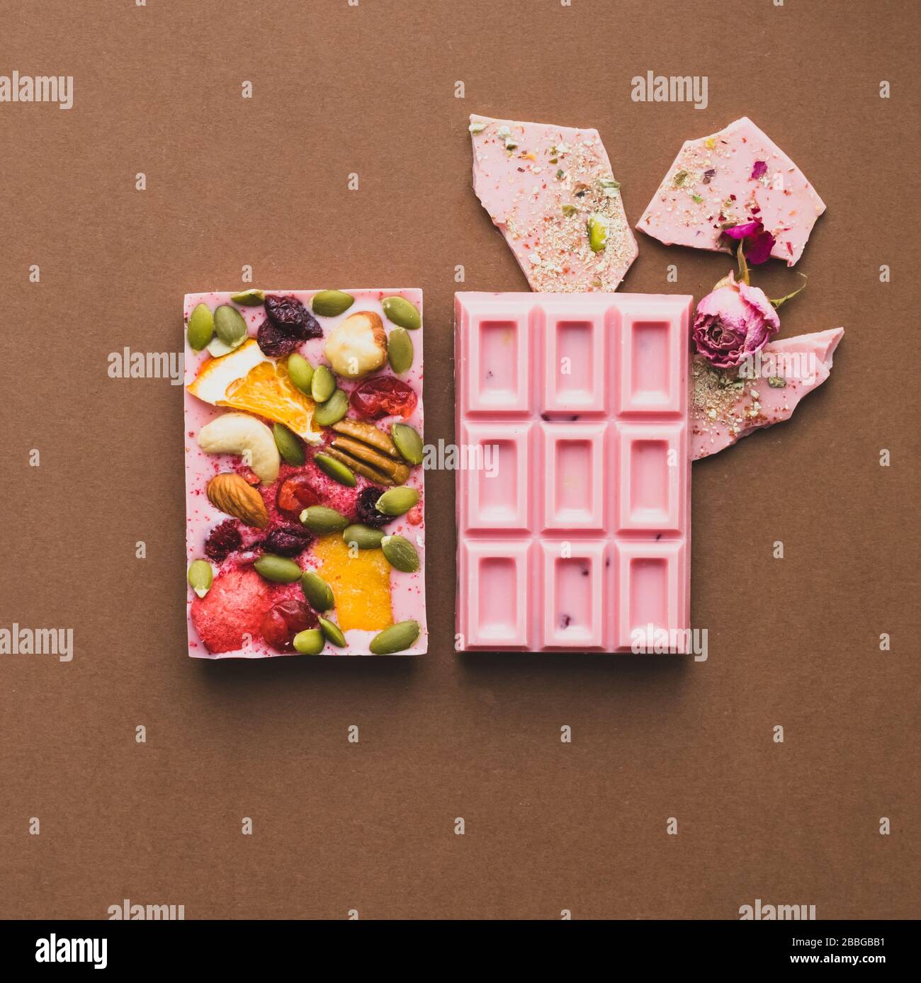Barra entera de color rosa chocolate decorada con rodajas de frutos secos y  rodajas de fondo marrón. Minimización Fotografía de stock - Alamy