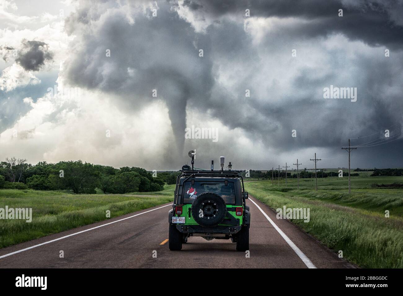 Tornado rasga la suciedad como jeep conduce hacia el campo de escombros cerca de Hays Kansas Estados Unidos Foto de stock