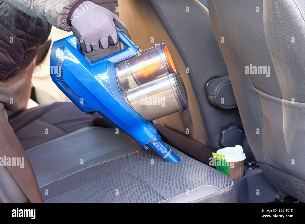 Aspirador en manos del conductor. Limpieza del interior del coche con una  aspiradora azul. Los asientos de tela de los coches se limpian regularmente  Fotografía de stock - Alamy