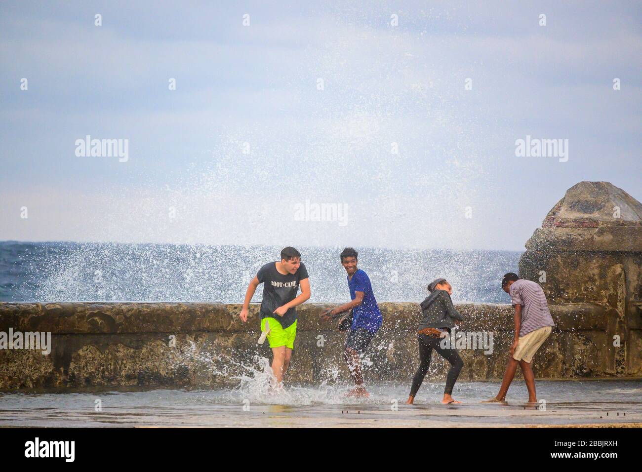 Un día tormentoso sopla olas sobre el Malecón, jóvenes que se asoman al spray, Centro, la Habana, Cuba Foto de stock