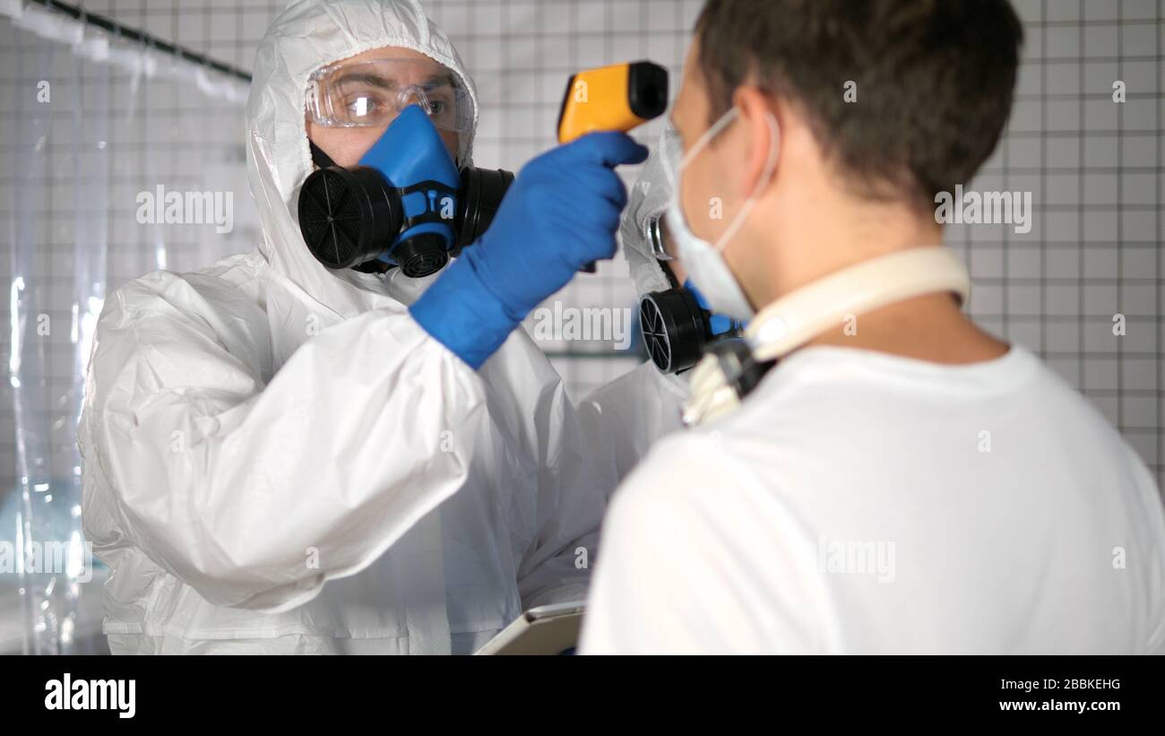 Médico en traje protector usando pirómetro para medir la temperatura de las  personas en un hospital Fotografía de stock - Alamy