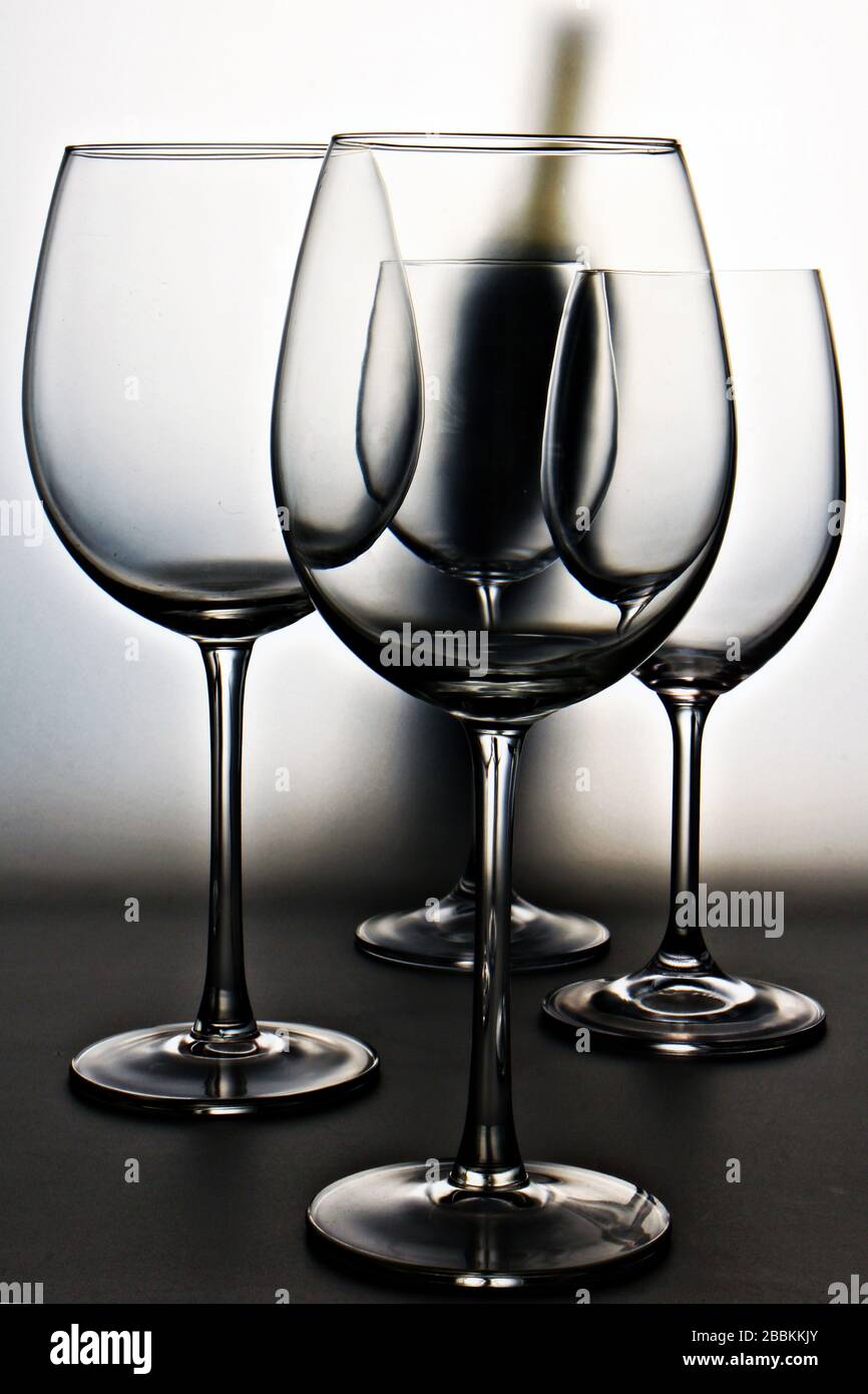 Primer plano de elegantes copas de vino sobre el fondo vertical de la botella de vino tinto Foto de stock