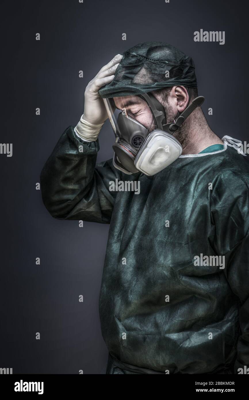 retrato de un médico con protecciones y máscara con filtros sosteniendo una mano en la frente, un signo de fatiga y depresión. Tema coronavirus y ep Foto de stock