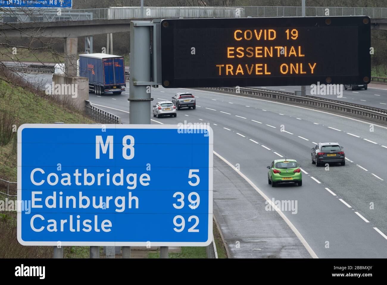 COVID-19 Essential Travel sólo señal en la autopista M8, Glasgow, Escocia, Reino Unido durante la pandemia de Coronavirus Foto de stock