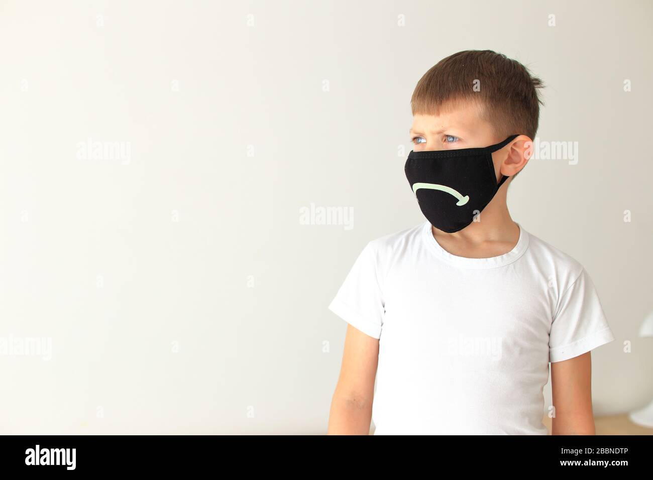 El niño se pone una máscara respiratoria en cuarentena en casa Foto de stock