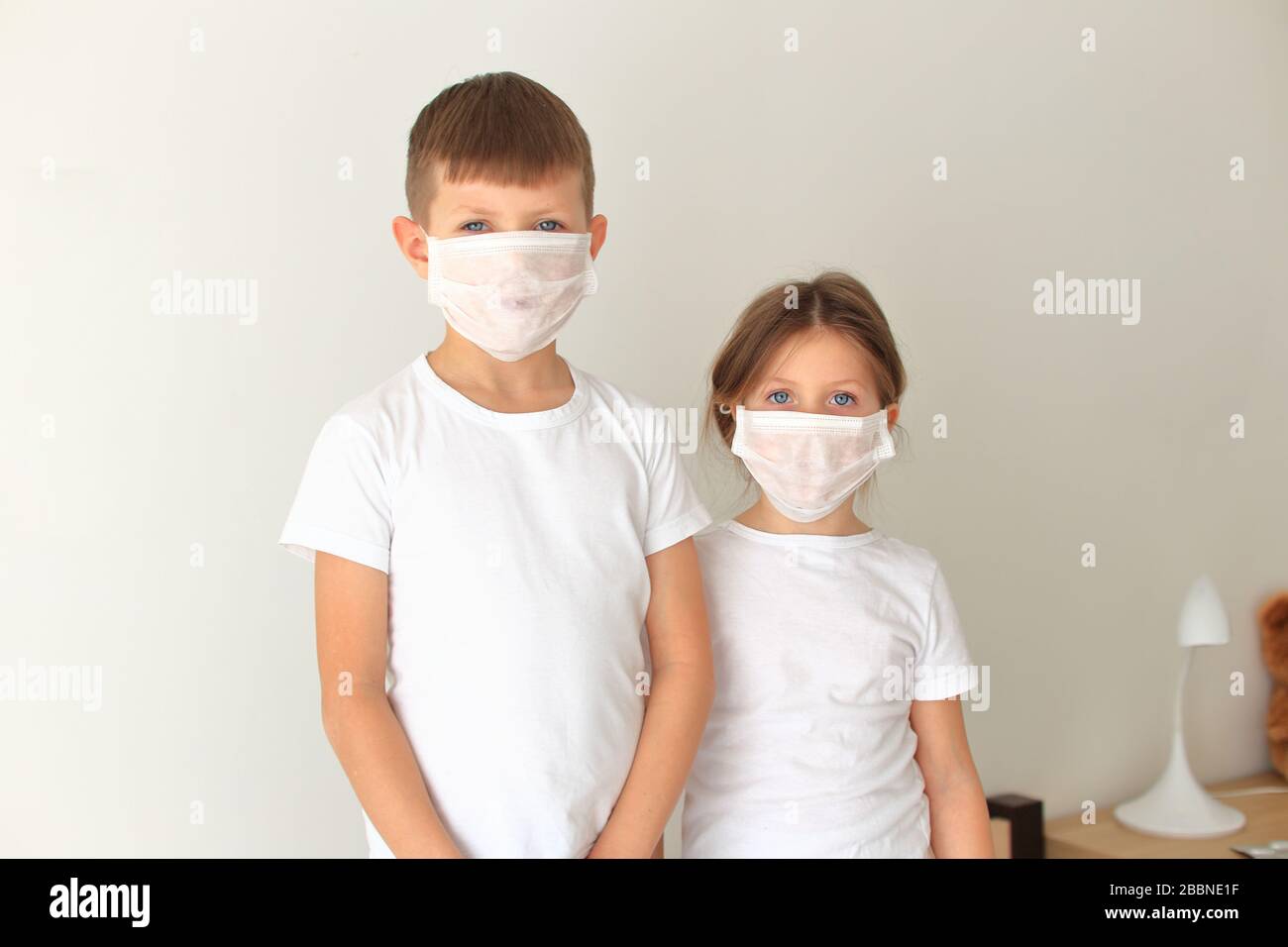 Los niños que se encuentran en una máscara respiratoria se encuentran en cuarentena en el hogar Foto de stock
