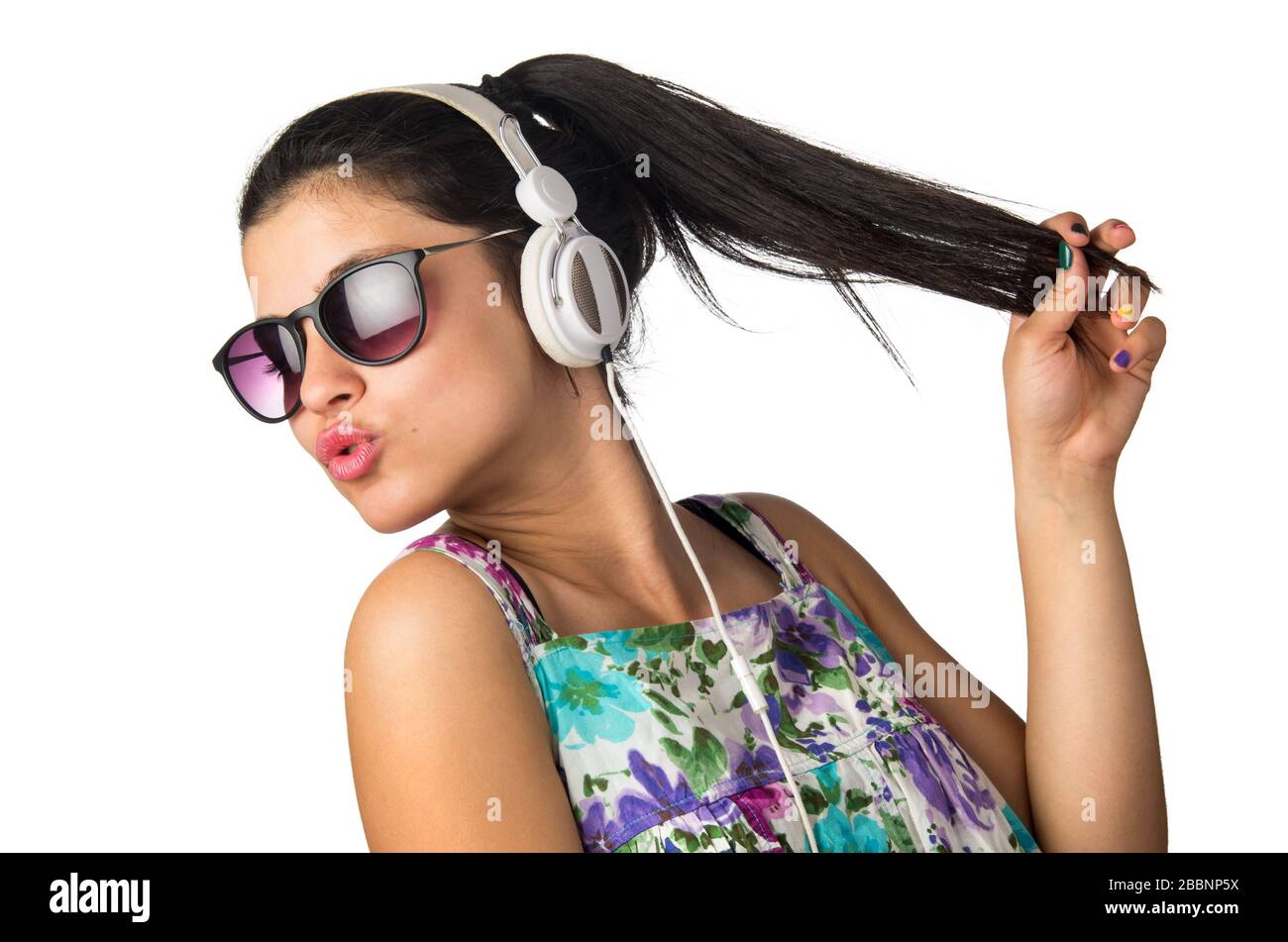 Bonita niña con auriculares y gafas de sol bailando y sosteniendo su cabello Foto de stock