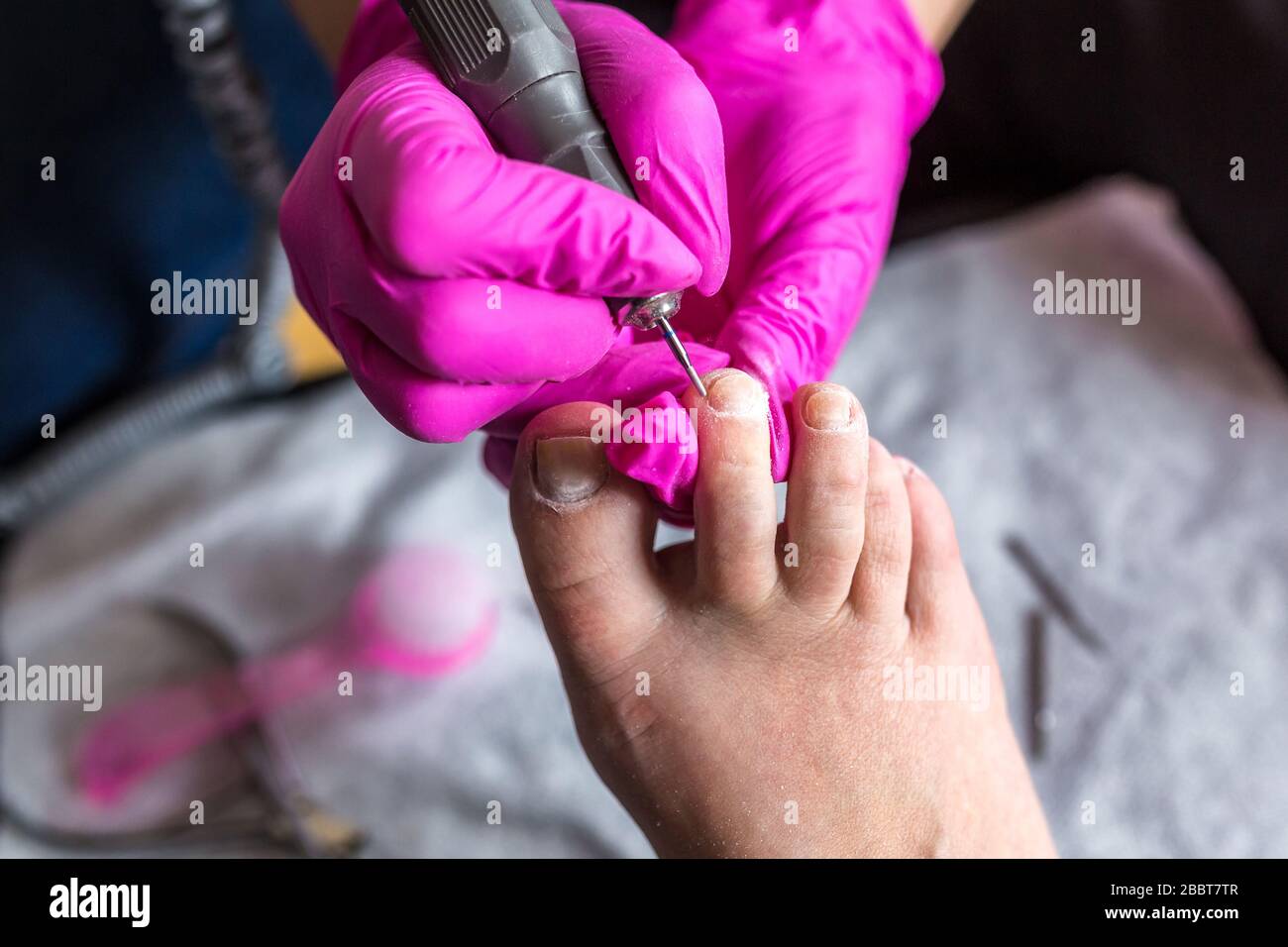 El maestro pediculista en guantes rosados corta la