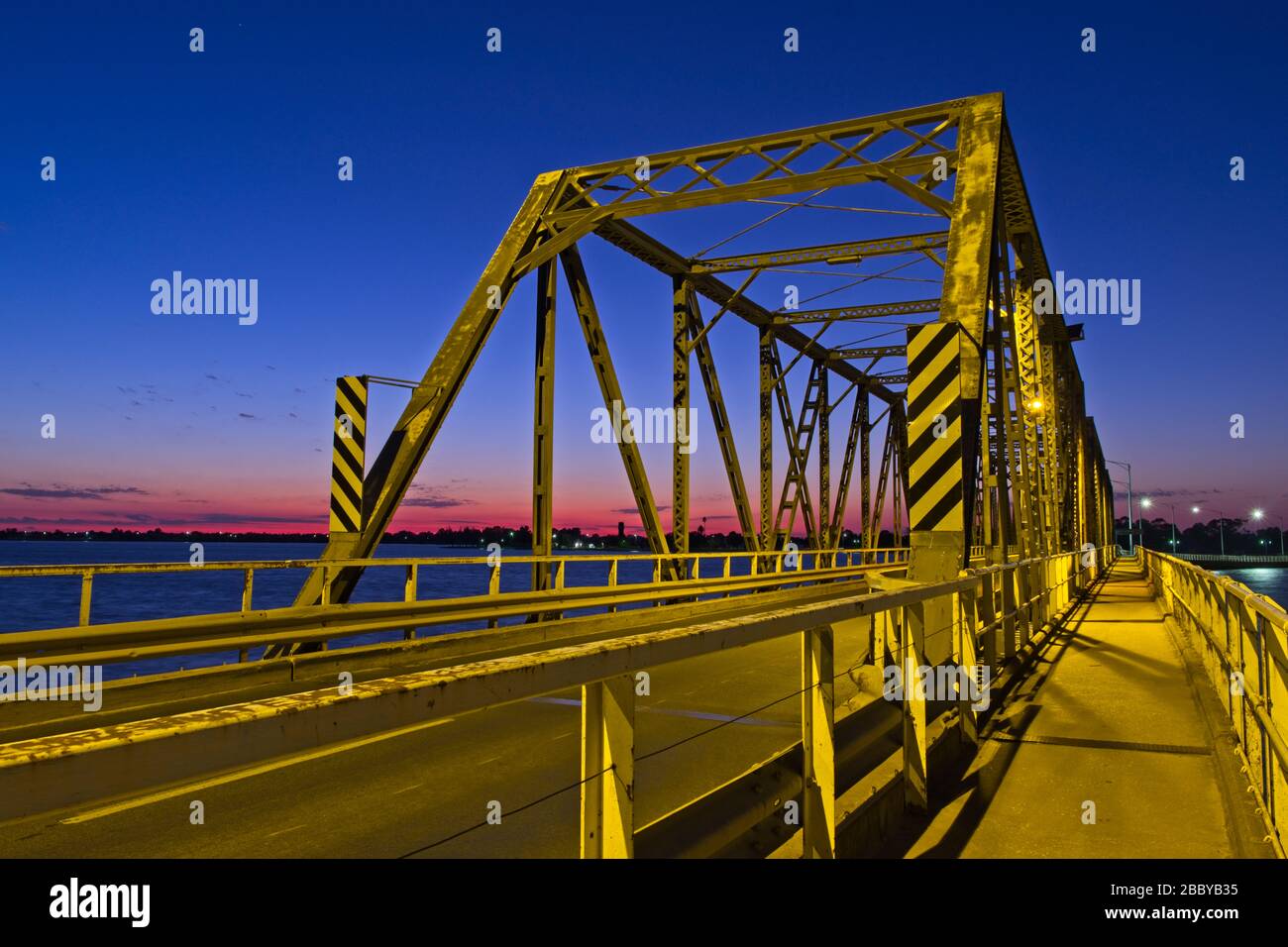 Un puente Mulwala amarillo al amanecer bajo un cielo azul profundo sobre un horizonte rosa Foto de stock