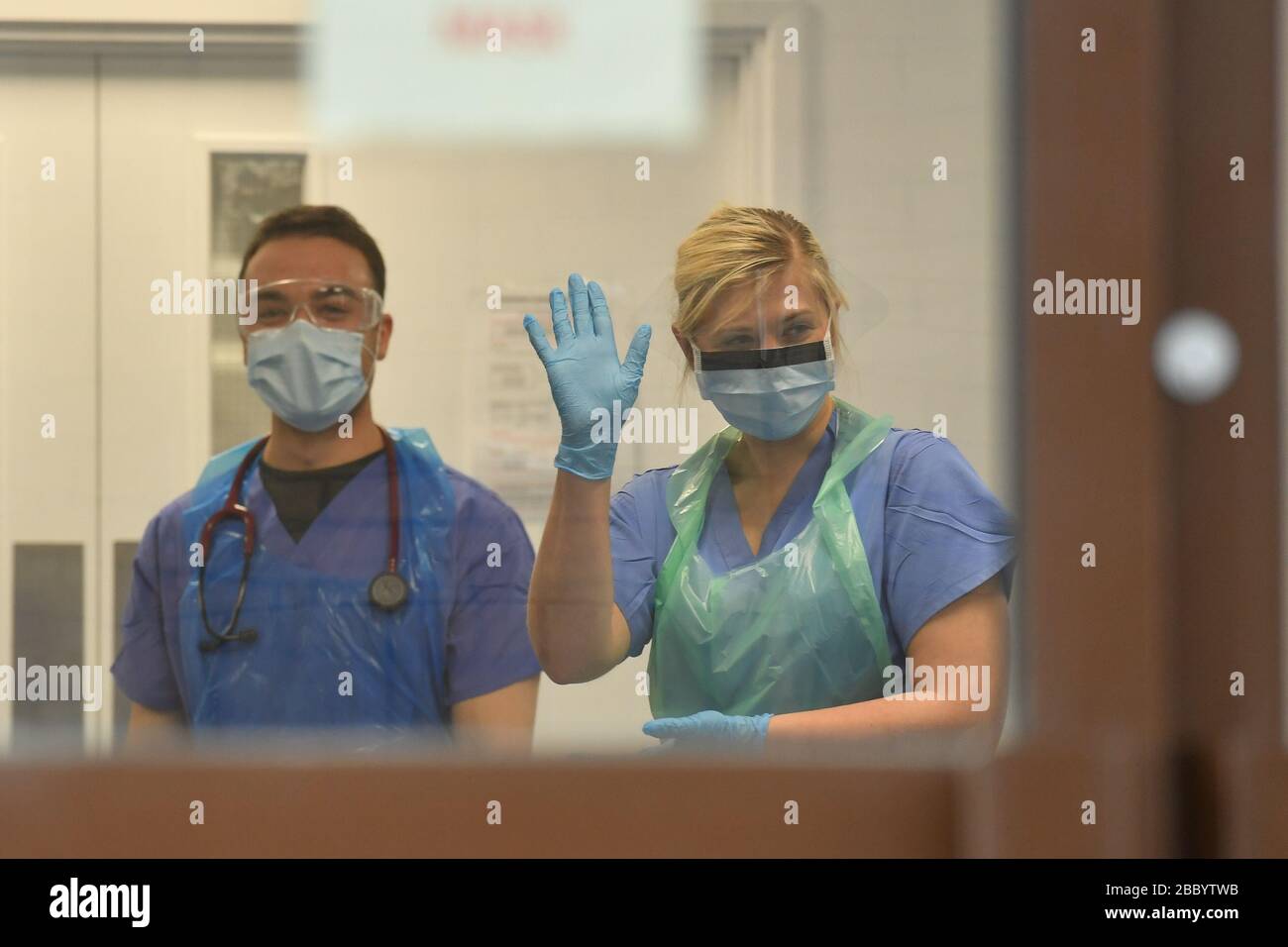 El personal médico que lleva equipo de protección personal (PPE) espera recibir a los pacientes con coronavirus en la puerta de la Unidad de Evaluación respiratoria del Hospital Morriston de Swansea, mientras los servicios de salud preparan su respuesta al brote de coronavirus. Foto de stock