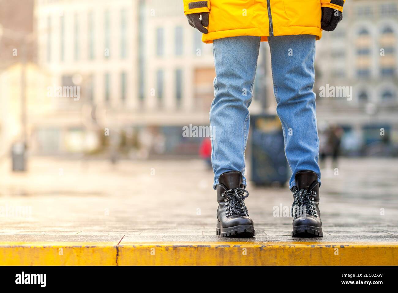 La niña está sentada en el camino en pantalones impermeables en un día frío  y soleado de invierno