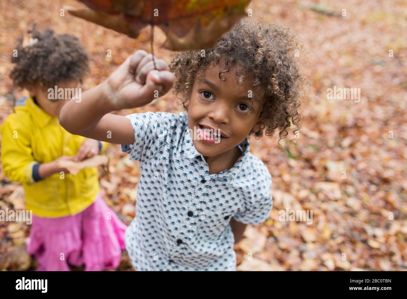 Retrato juguetón niño sosteniendo la hoja de otoño Foto de stock