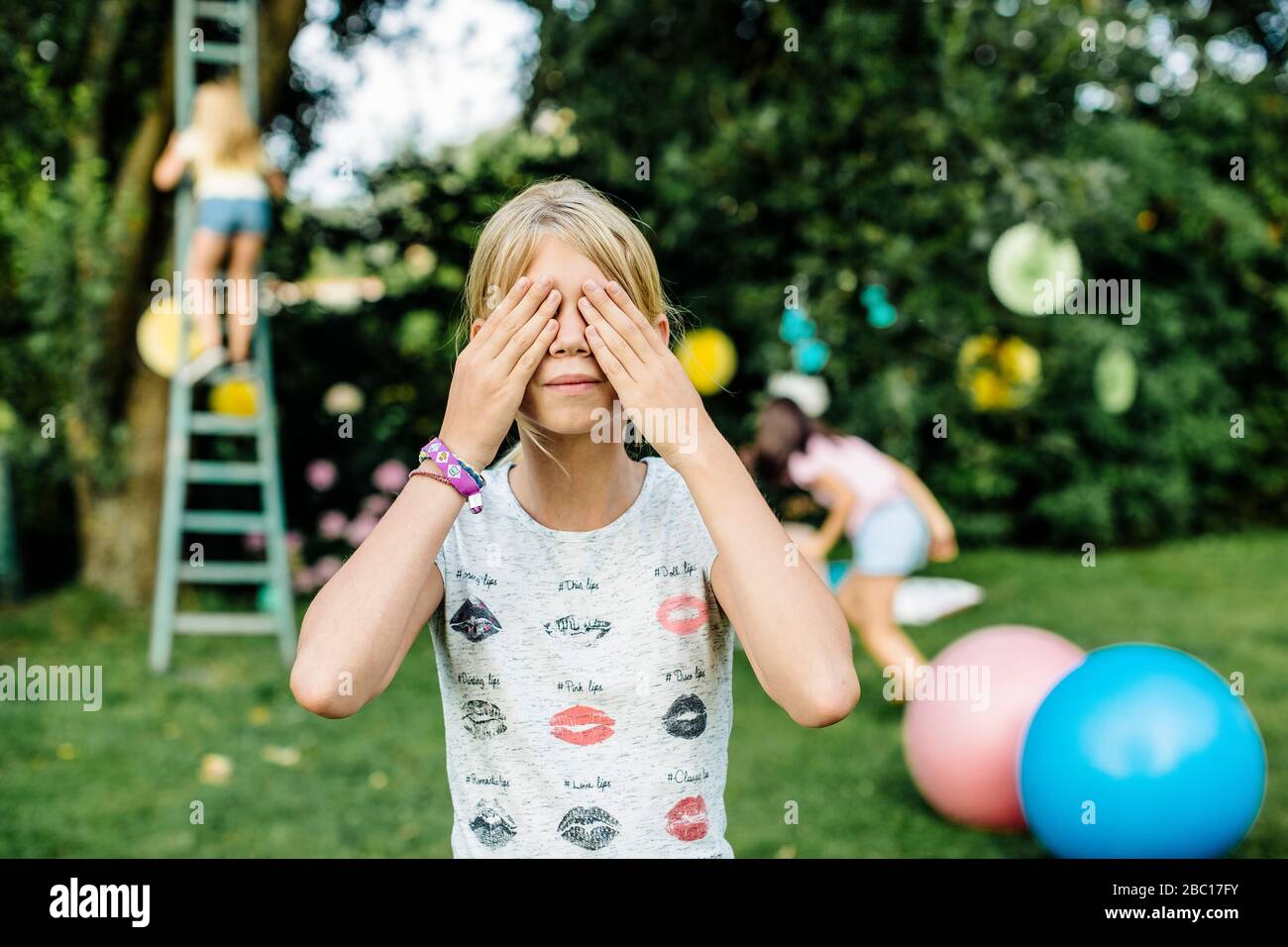 Las niñas jugando esconden y buscan en una fiesta de cumpleaños al aire libre Foto de stock