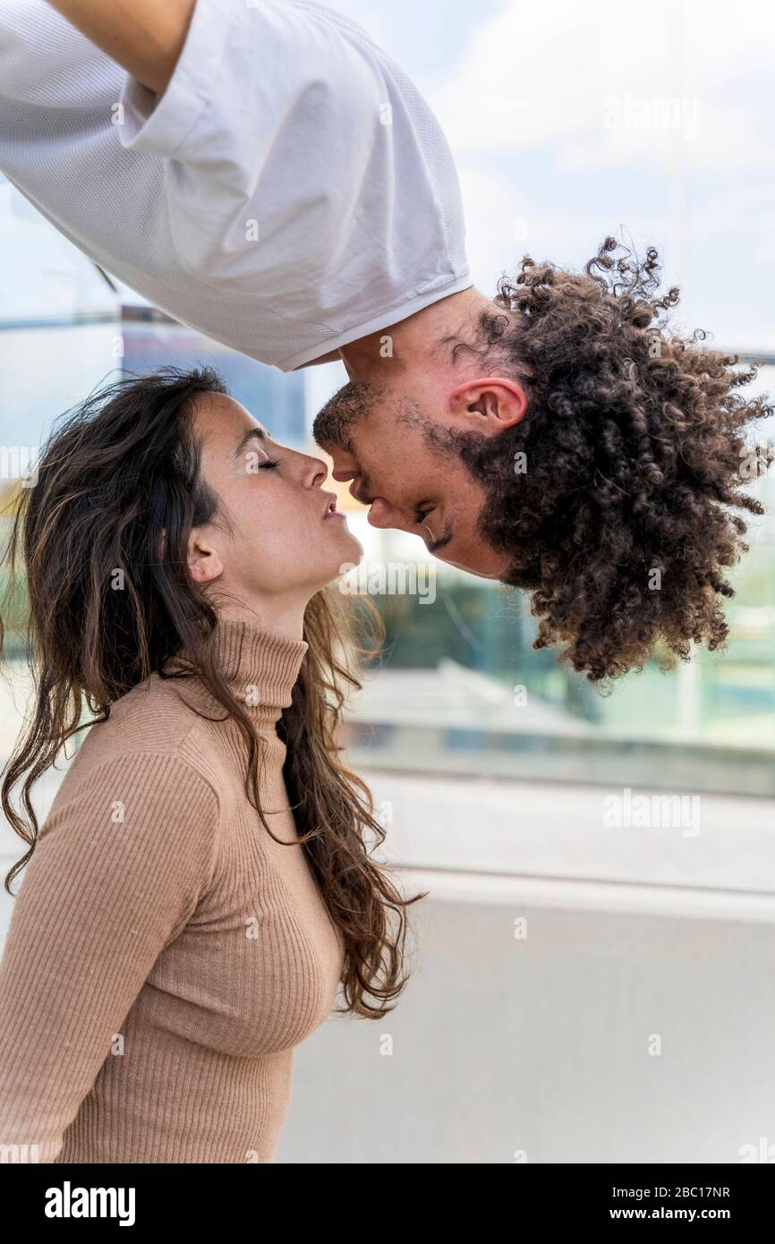 Besando a la pareja con una pareja colgando boca abajo Foto de stock