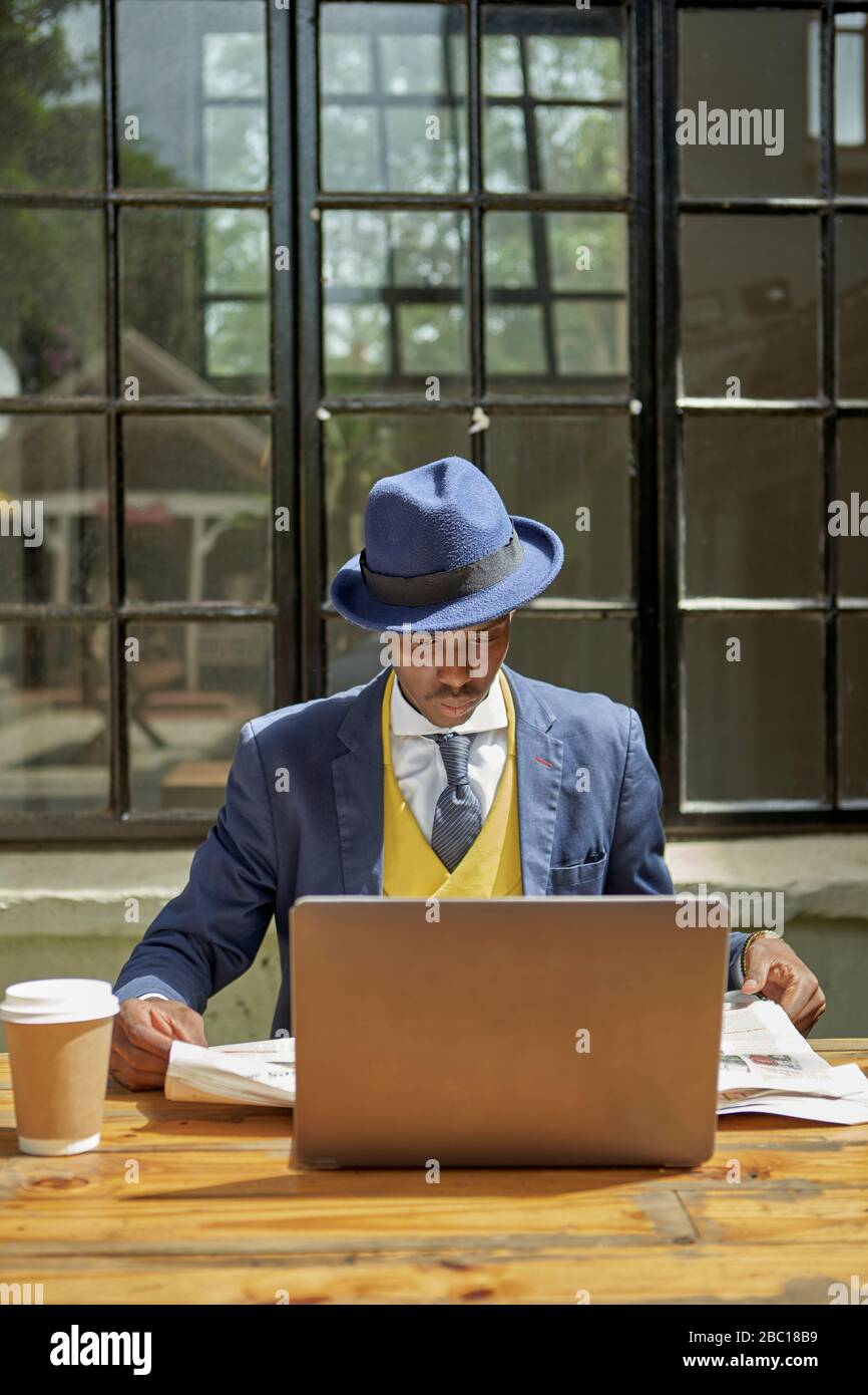 Joven hombre de negocios vestido traje de antaño y sombrero leyendo el  periódico en un café al aire libre Fotografía de stock - Alamy