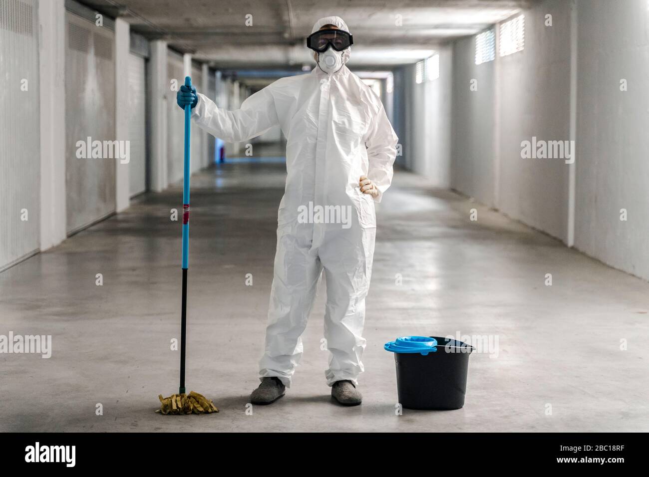 Mujer usando ropa protectora limpiando el suelo del aparcamiento Foto de stock