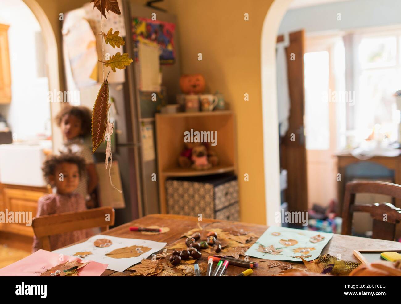 Niños de pie detrás de la mesa cubiertos con artesanías de otoño Foto de stock