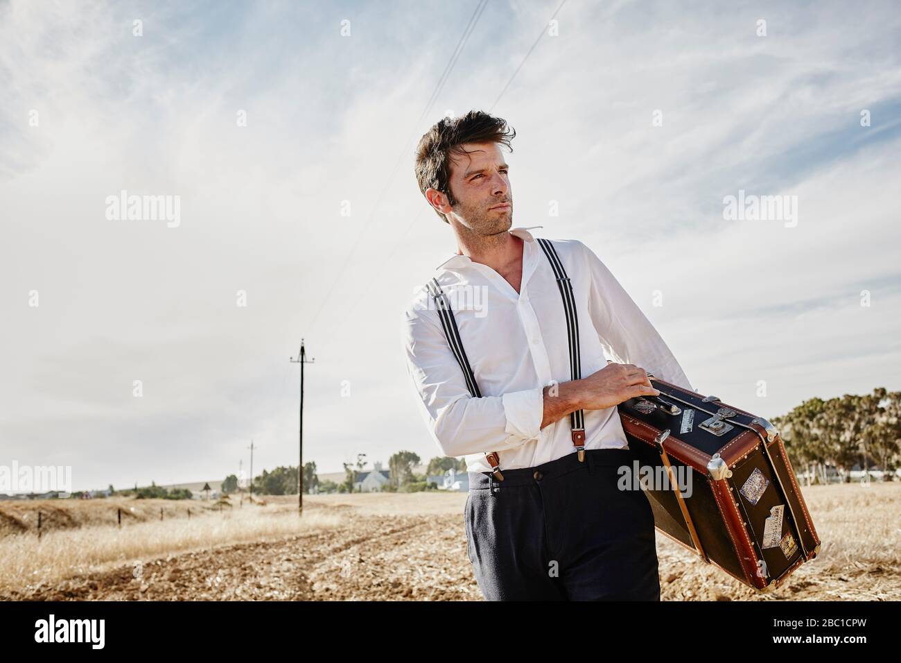 Hombre con ropa antigua y maleta en el campo Fotografía de stock - Alamy