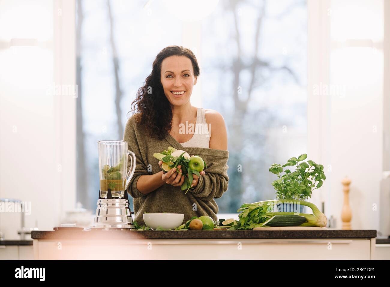 Mujer de pie en la cocina, preparar batidos saludables Foto de stock