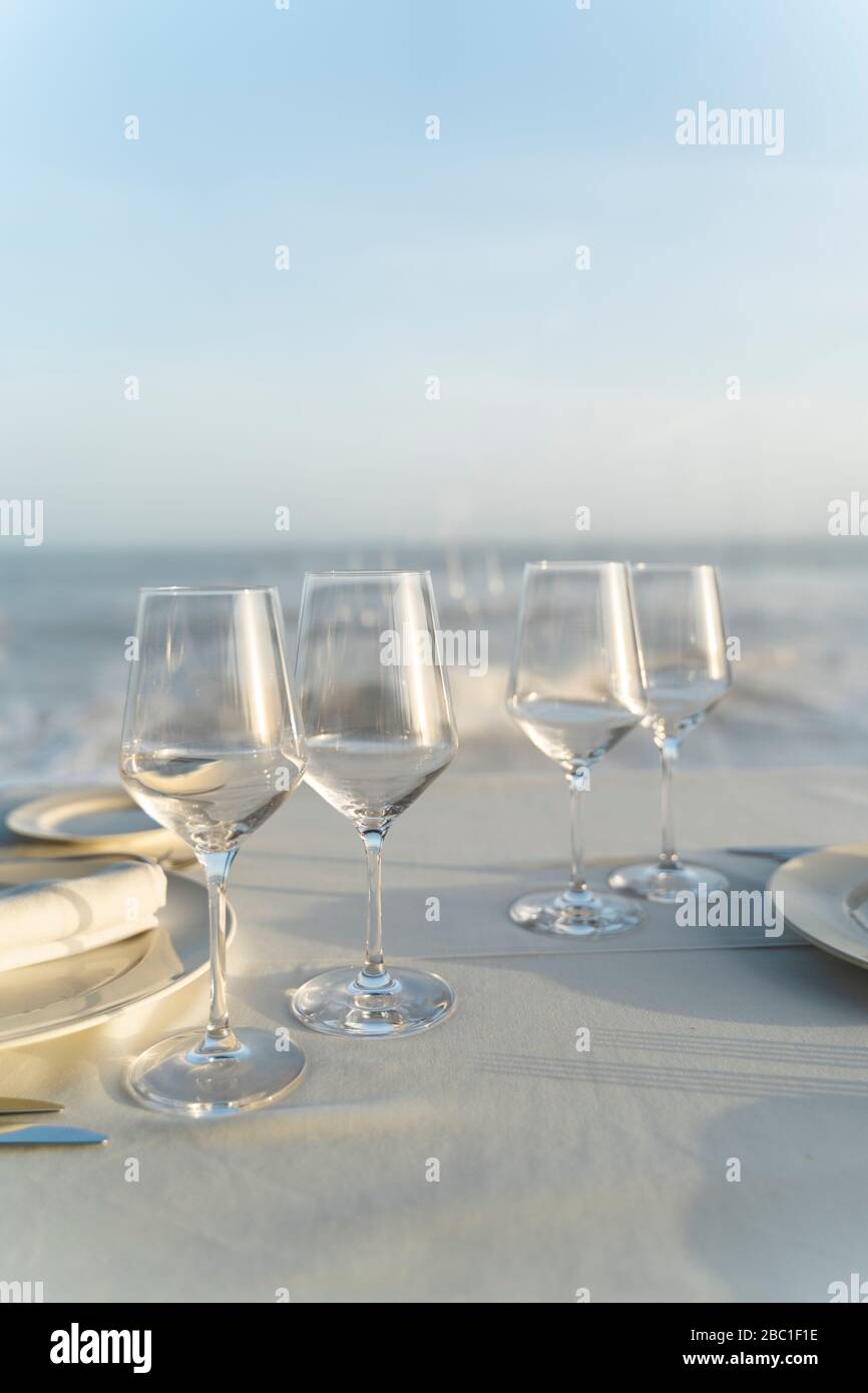 España, Vacilasses vacíos en mesa de restaurante con el mar en el fondo Foto de stock