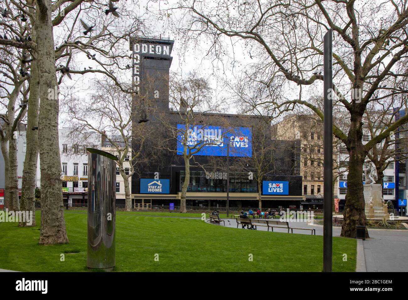 Una Leicester Square casi desierta en el centro de Londres durante el brote del virus de la corona. El Odeon Cinema tiene señales que avisan a la gente de que salve vidas, etc. Foto de stock