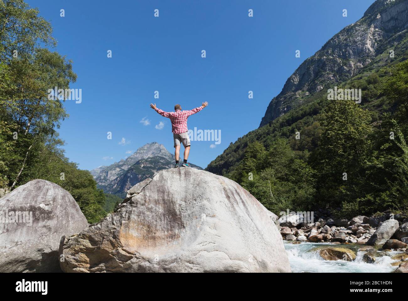 Hombre de pie sobre roca en el río Verzasca, Valle Verzasca, Ticino, Suiza Foto de stock