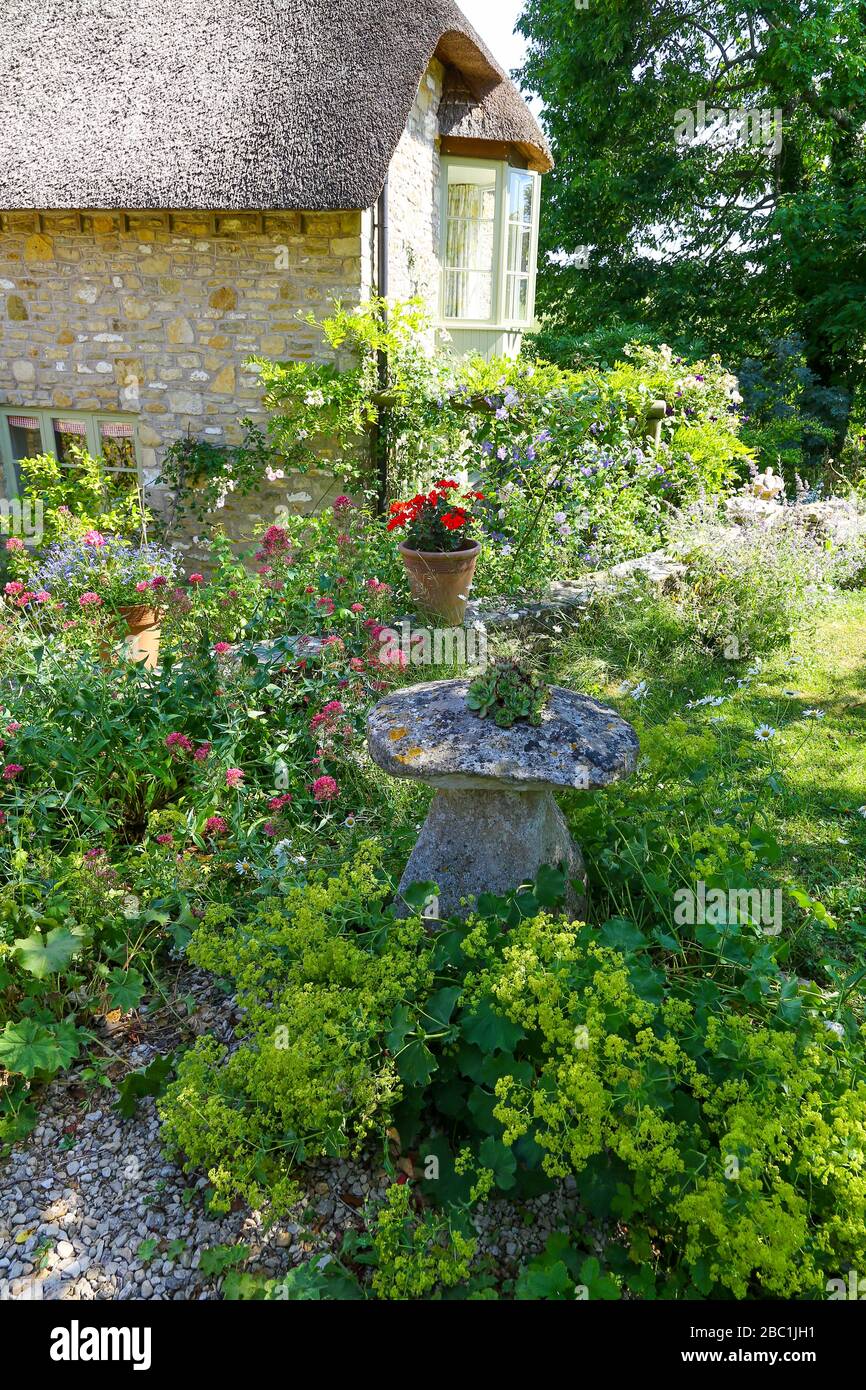Una piedra a caballo, o hongo de piedra, utilizado como una característica decorativa del jardín en un jardín inglés de la cabaña de paja, Batcombe, Somerset, Inglaterra, Reino Unido Foto de stock