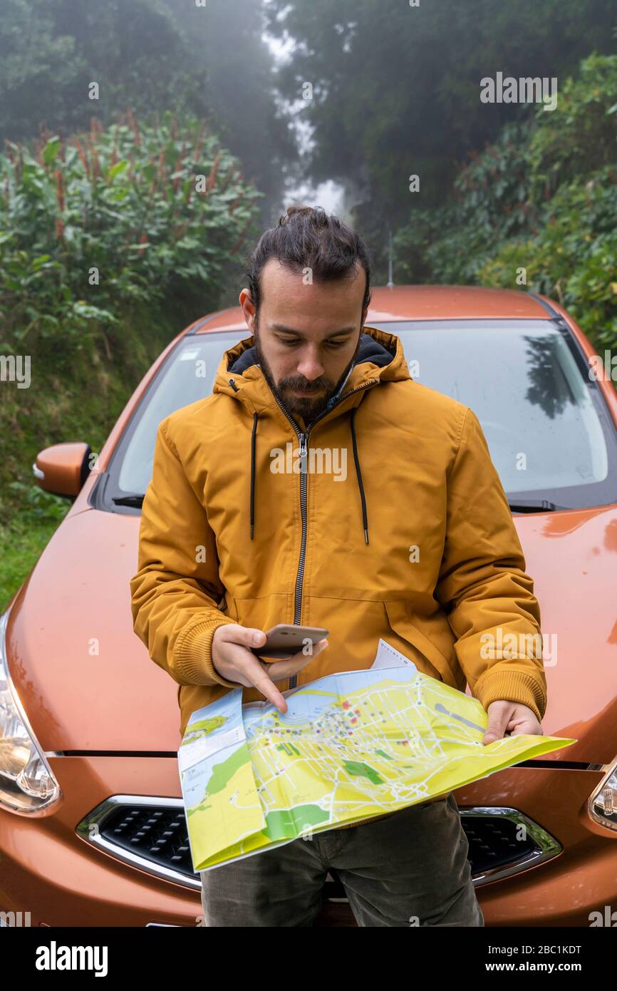 mapa carreteras sao miguel azores Hombre con smartphone y mapa fuera de coche en carretera forestal 