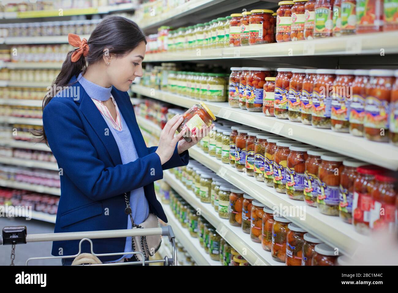 Mujer leyendo etiqueta en el frasco en el supermercado Foto de stock
