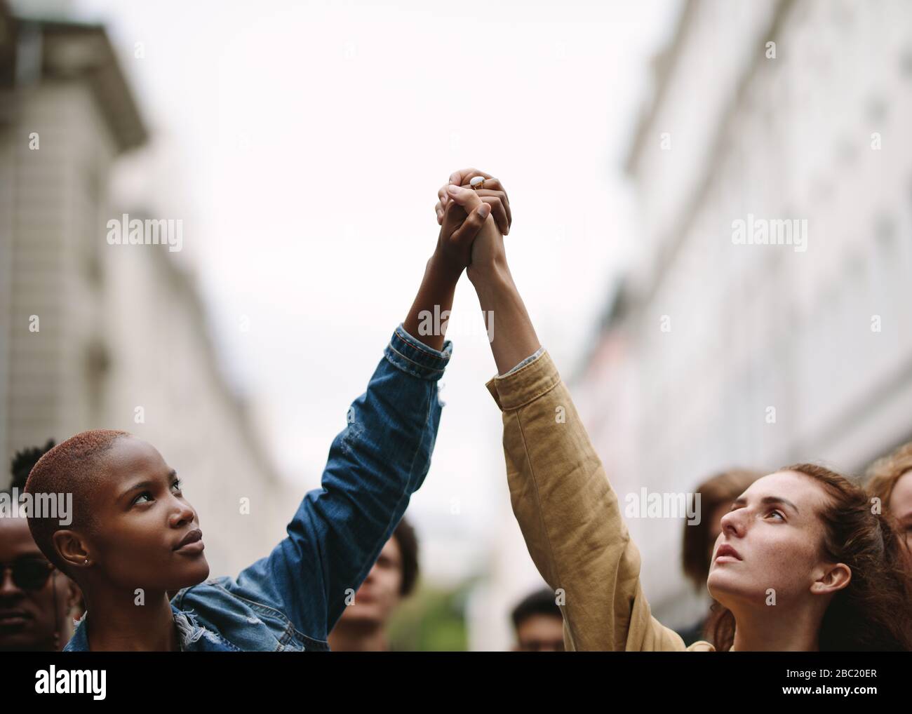 Dos mujeres activistas se aferran y protestan. Manifestantes haciendo manifestación en la calle con las manos. Foto de stock