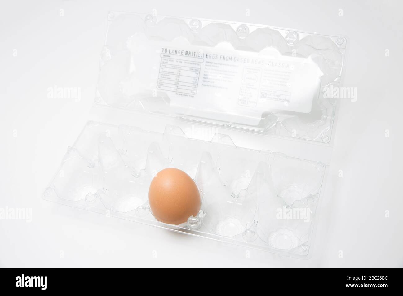 Un solo huevo sin cocer de una gallina enjaulada en una caja de plástico. Los huevos fueron uno de los varios artículos que se agotaron rápidamente durante el brote de Coronavirus. Sí Foto de stock