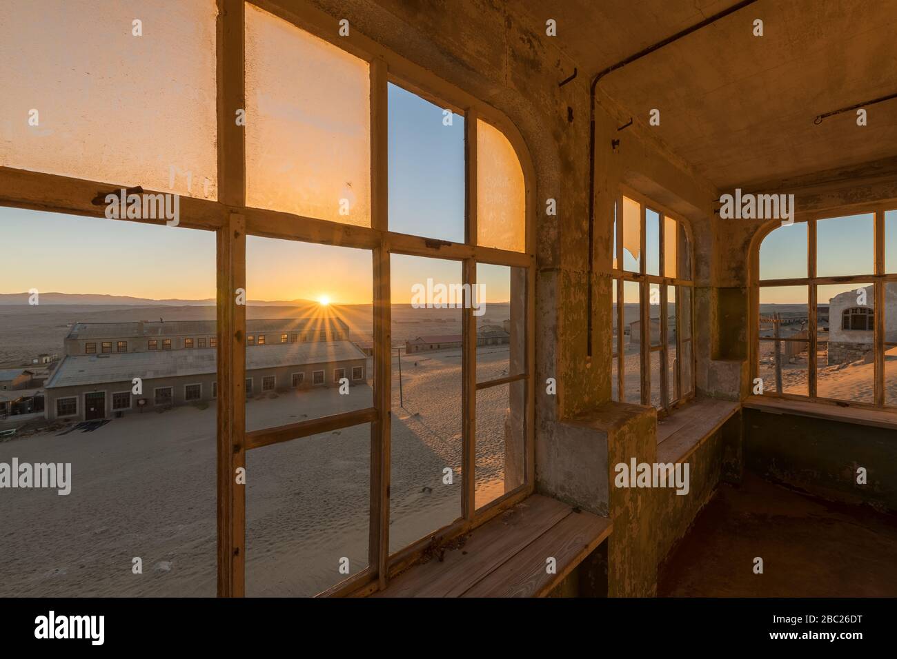 Una fotografía dramática dentro de una casa abandonada al amanecer, con una explosión de sol dorada y la construcción a través de ventanas rotas, tomada en la ciudad fantasma de Ko Foto de stock