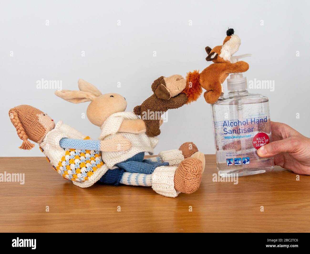 Imagen conceptual que ilustra la escasez de gel desinfectante para manos como juguetes peludos tratan desesperadamente de colgar en una botella de gel desinfectante para manos. Foto de stock