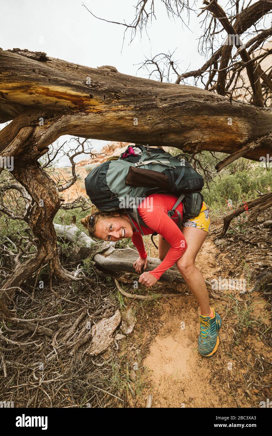 sonríe todo el día para mujer caminando en el desierto y esquivando bajo el árbol muerto Foto de stock