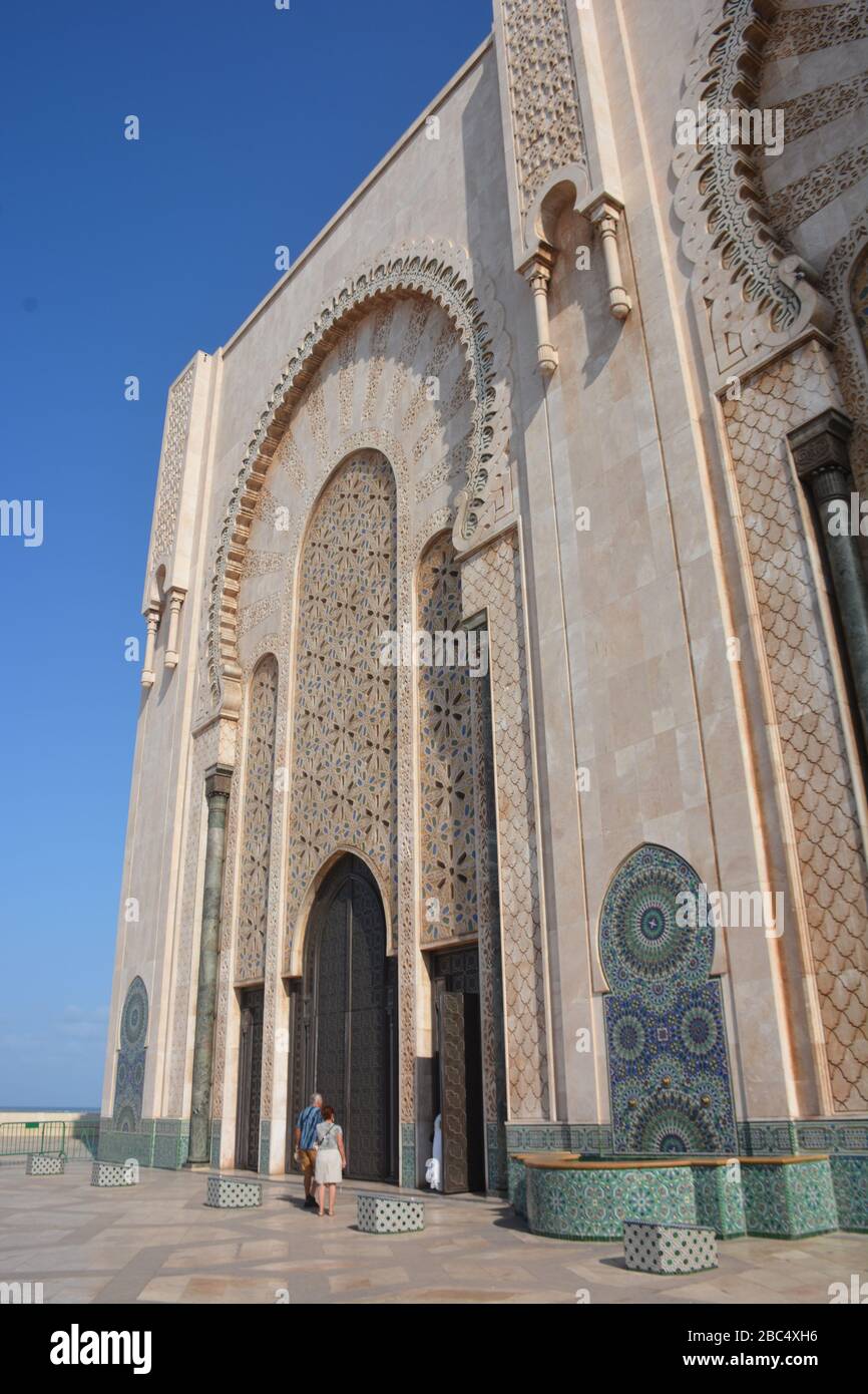 Un par de turistas occidentales en la entrada principal de la Mezquita Hassan II en Casablanca, Marruecos. El edificio es la mezquita en funcionamiento más grande de África. Foto de stock
