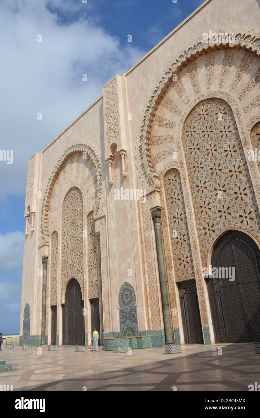 Un trabajador se encuentra fuera de la entrada principal de la Mezquita Hassan II, Casablanca, Marruecos, la séptima mezquita más grande del mundo y la segunda más grande de África. Foto de stock