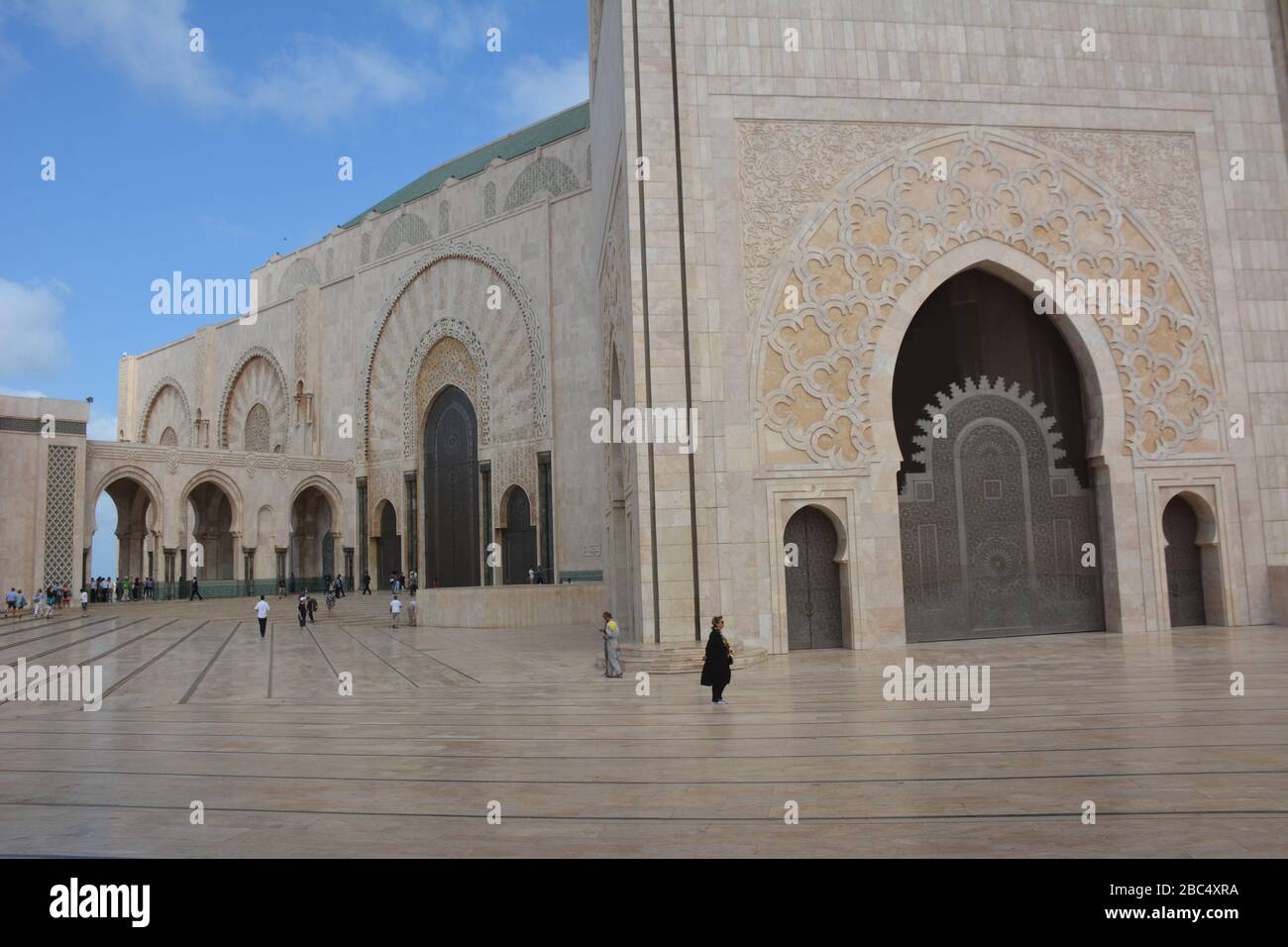 Espectacular foto exterior de la Mezquita Hassan II, Casablanca, Marruecos, mostrando el enorme tamaño del edificio en comparación con la gente. Foto de stock