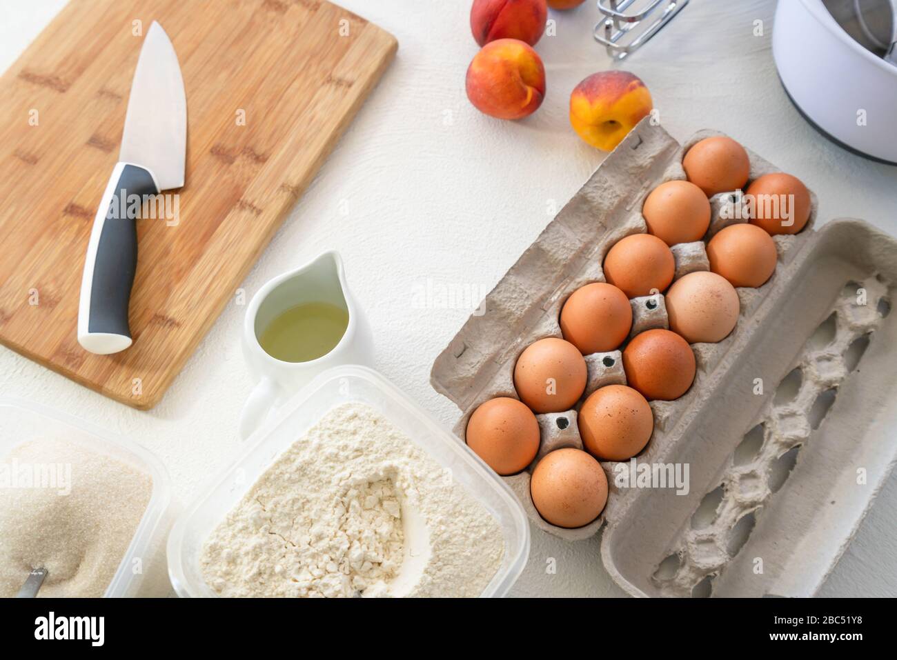 Ingredientes de la receta del pastel de melocotón. Huevos, azúcar, harina, aceite  vegetal, melocotones frescos cerca sobre fondo blanco, vista superior  Fotografía de stock - Alamy